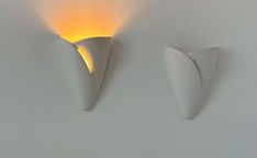 two white wall sconces with yellow light coming from one side and another on the other