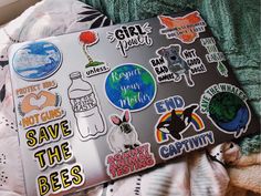 an open laptop computer sitting on top of a bed covered in stickers