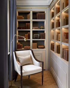 a white chair sitting in front of a book shelf filled with books