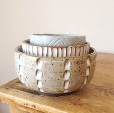 three ceramic bowls sitting on top of a wooden table