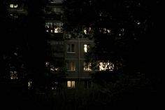 an apartment building lit up at night with trees in the foreground and lights on