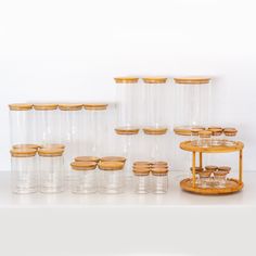 there are many glass jars and wooden lids on the table with each one in front of them