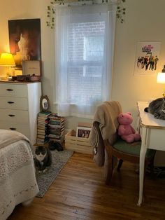 a bedroom with a bed, desk and two stuffed animals on the chair in front of the window