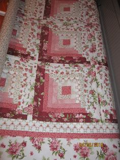 a pink and white quilt on top of a bed