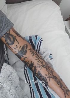 a person laying in bed with a tattoo on their arm and leg next to a blanket