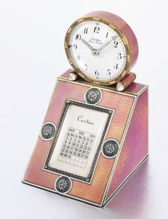 a pink and gold clock sitting on top of a desk