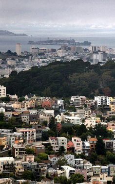 an aerial view of a city with lots of tall buildings in the foreground and water in the background