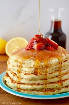 a stack of pancakes with syrup and strawberries on top, sitting on a blue plate