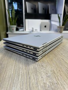 four apple laptops are stacked on top of each other in front of a desk