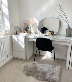 a white desk topped with a mirror and a black chair next to a radiator