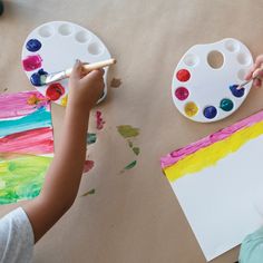 two children are painting on paper with paintbrushes and watercolors in front of them