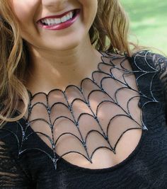 a close up of a woman wearing a black top with spider webs on it