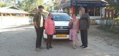 three people are standing in front of a car