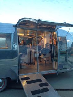 an airstream is parked on the side of the road with its doors open and people inside