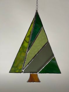 a stained glass christmas tree ornament hanging from a chain