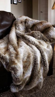 an animal fur blanket on top of a leather chair in a living room next to a fireplace