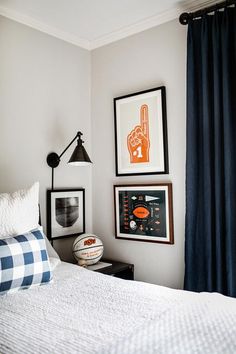 a bed room with a neatly made bed and pictures hanging on the wall above it