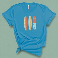 This retro summer beach surfboard t-shirt for women is for those that know surfing is a way of life. This is perfect for any summer vacation outfit. Grab this t-shirt if you are a big fan of surfing and a lover of the beach. This summer, walk down the boardwalk wearing this fun retro graphic tank top and feel some awesome beach vibes. This graphic t-shirt is for all surf lovers, surfers, and wave riders! You will look great in this surfboard t- shirt showing off your surfer spirit. DETAILS This Casual Short Sleeve T-shirt For Water Sports, Blue Beach T-shirt With Front Print, Blue Top For Summer Water Sports, Blue Summer T-shirt For Surfing, Retro Surfing T-shirt For Beach Season, Summer Water Sports Short Sleeve T-shirt, Crew Neck Tops For Water Sports In Summer, Retro Funny Print T-shirt For Beach, Blue Crew Neck Tops For Water Sports