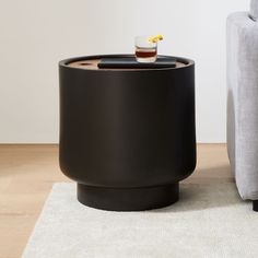 a black table sitting on top of a wooden floor next to a gray couch and white rug