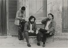 three men sitting on the steps with one man wearing a mask over his face and another holding a cell phone to his ear