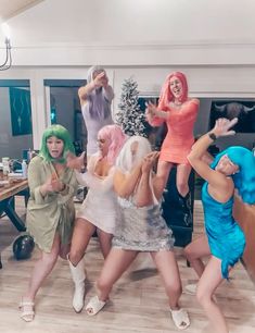 four women dressed in costumes are dancing together on the dance floor with their hands up