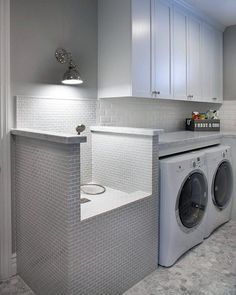 a washer and dryer in a room with white cupboards on the wall