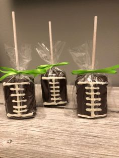 three chocolate covered candies wrapped in cellophane and tied with green ribbon, sitting on a wooden table