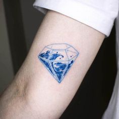 a blue diamond tattoo on the left arm with water splashing out of it's center