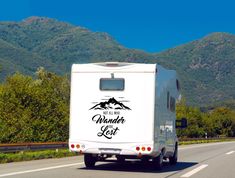 an rv traveling down the road with mountains in the background