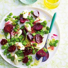 a white plate topped with beets and green beans next to a bowl of mustard