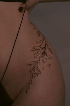 a woman's back with a tattoo on her left side and flowers in the middle