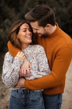 a man and woman hugging each other on a dirt path