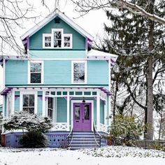 a blue house with purple trim and white windows in the front yard covered in snow