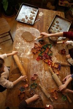 children are making cookies on a wooden table