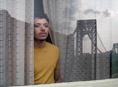 a man standing in front of a window next to a bridge