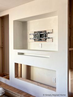 an empty room with white walls and wooden shelves in the wall, including a clock