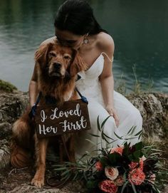 a woman in a wedding dress sitting next to a dog holding a sign that says i loved her first