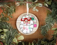 a wooden ornament hanging from a tree with pine branches and greenery around it