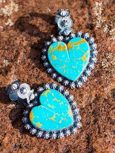 Beautiful custom cut turquoise heart pendants, surrounded with our sterling shot bead Conchos. Shot beads are solid silver and are very tedious and time consuming to produce. I love these with our braided kangaroo leather necklaces. Brilliant blue and green Kingman turquoise in pillow cut - what a fun pendant! Fluted shot bead top, sterling silver shot bead bezel set. This pendant finished about 1 3/4 inches. Hearts can take a little time to cut, custom build is 4 - 6 weeks. Contact us for avail Artisan Heart Pendant Jewelry, Bohemian Turquoise Heart Jewelry, Artisan Engraved Heart Jewelry, Artisan Engraved Heart-shaped Jewelry, Handmade Blue Western Jewelry, Western Style Engraved Blue Jewelry, Handmade Western Blue Jewelry, Unique Turquoise Jewelry With Sterling Silver Clasp, Blue Western Sterling Silver Jewelry