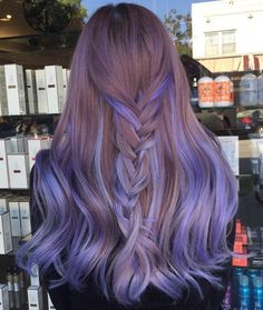 a woman with long, purple hair is seen from the back in front of a store window