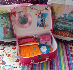 an open pink suitcase sitting on top of a bed next to pillows and pillow cases