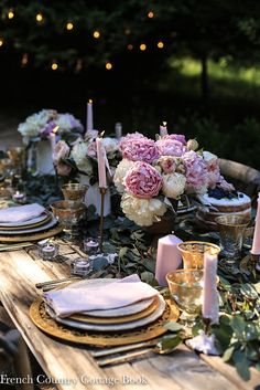 the table is set with candles, plates and flowers in vases on top of it