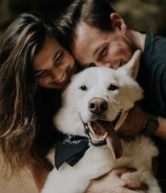 a man and woman are hugging their dog