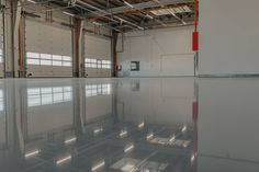 the inside of an industrial building with reflective flooring and large windows on each side