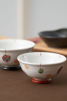 two white bowls sitting on top of a table next to each other with designs on them