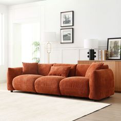 an orange couch sitting on top of a wooden floor next to a white rug in a living room