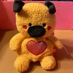 a yellow teddy bear with a heart on it's chest sitting on a table