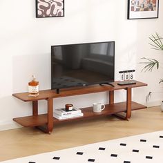 a flat screen tv sitting on top of a wooden stand in a living room next to a potted plant