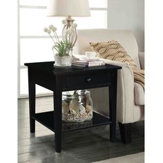 a black end table with glass jars and flowers on it next to a white couch