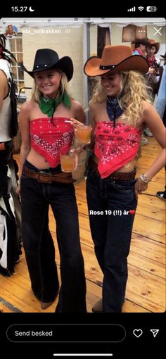 two women dressed in cowboy outfits and holding drinks, standing on a wooden floor next to each other